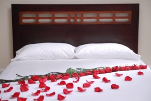 white hotel bed withe roses and petals on it